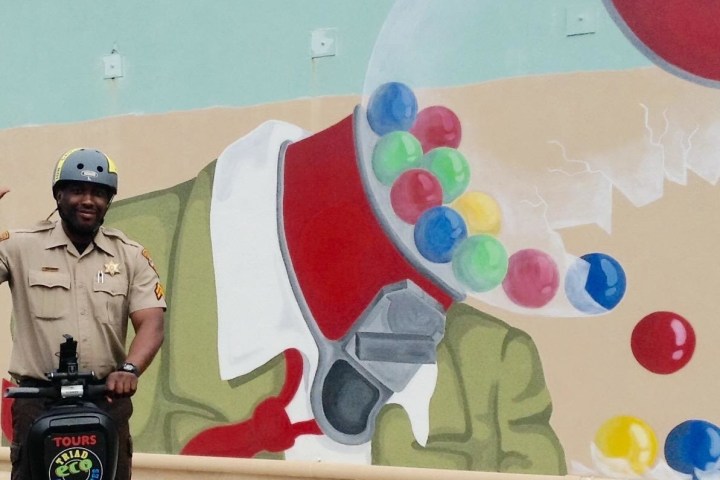 Sherif waving hi on a segway in front of a mural of a gumball machine losing its gumballs